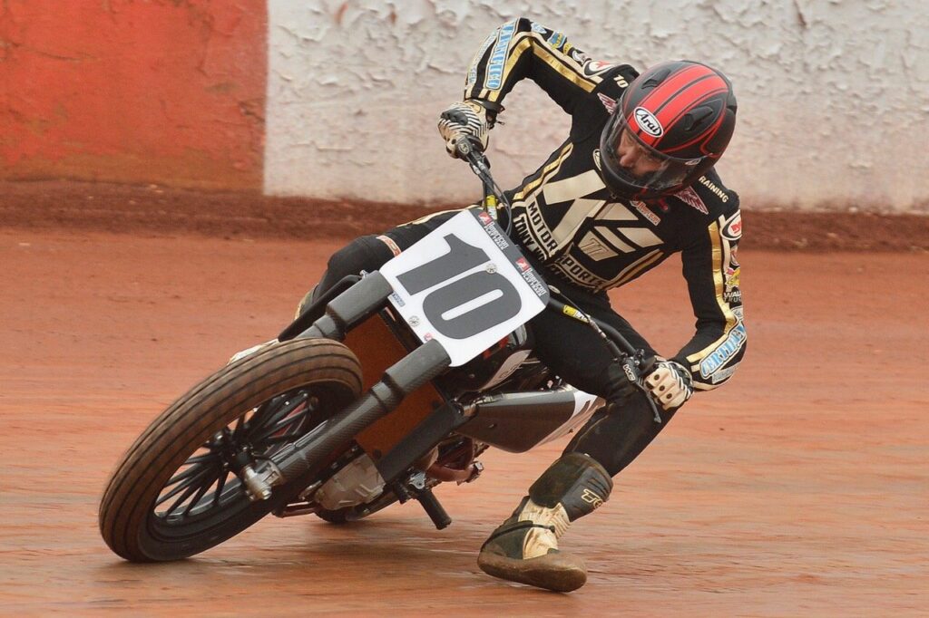 Flat track racer number 10 leaning into a turn on a clay oval